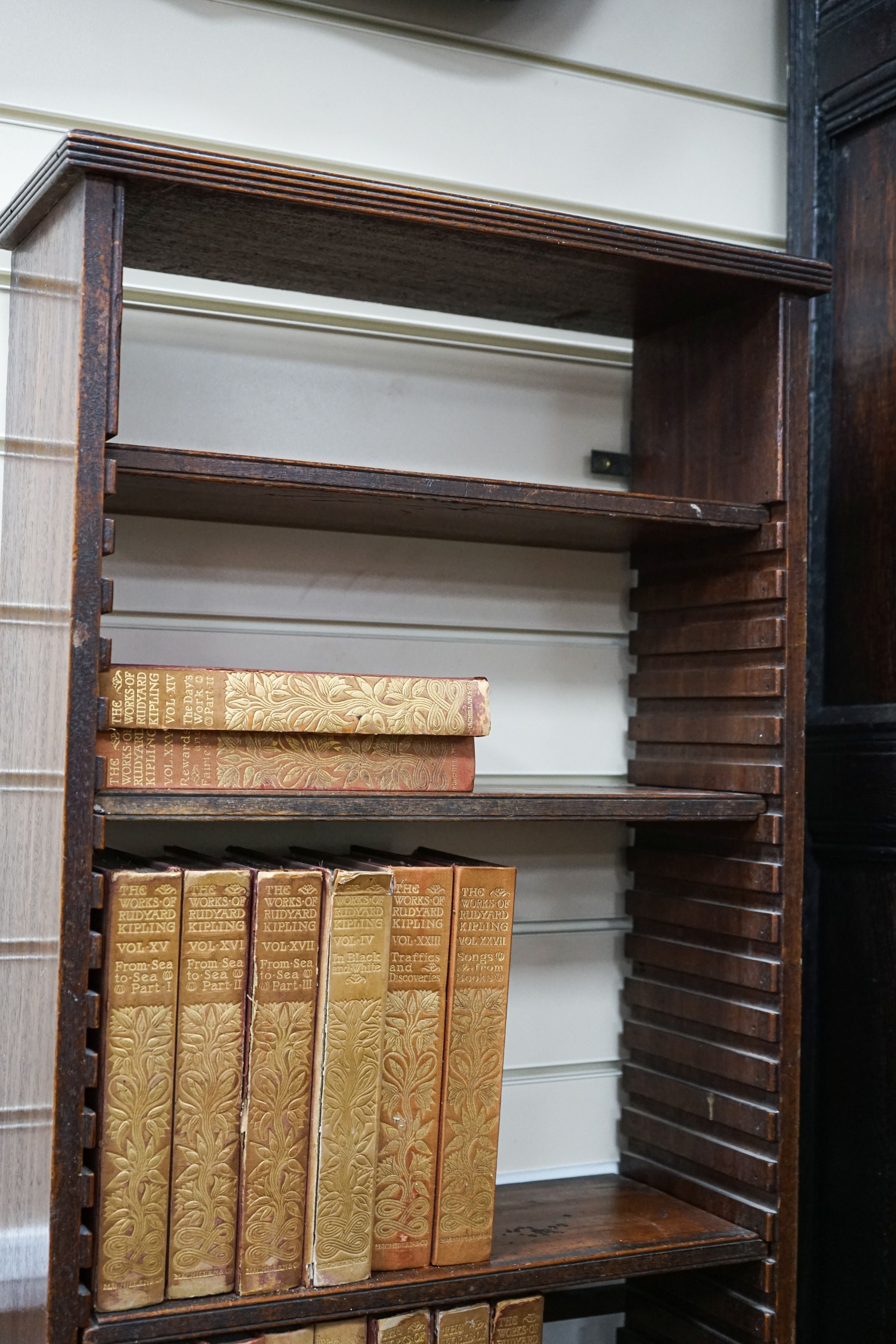 A Georgian mahogany wall-mounted narrow bookshelf, width 48cm, depth 18cm, height 147cm, containing a limited edition Works of Rudyard Kipling in 33 volumes, published 1900